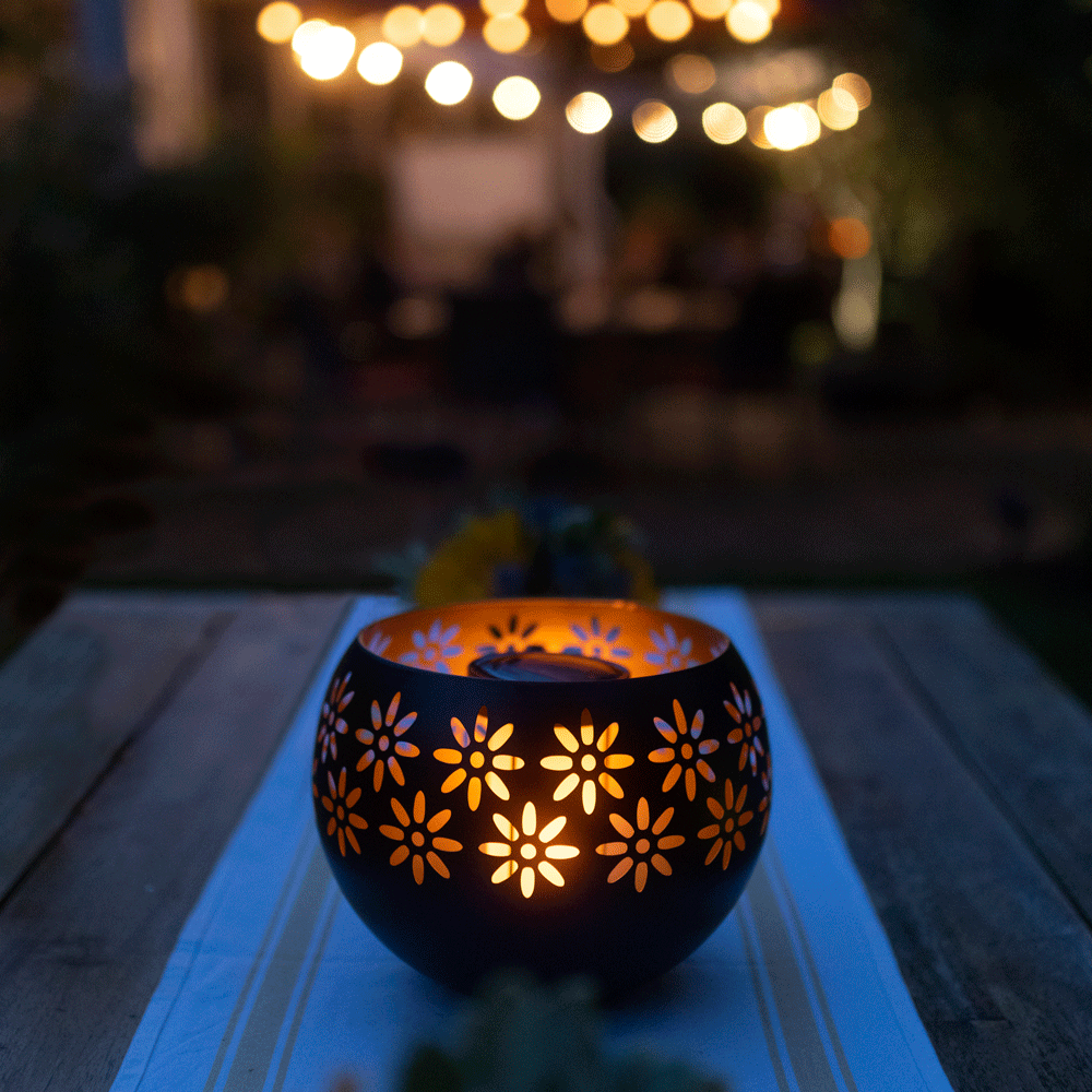 Decorative lantern with floral patterns on a wooden table at night.