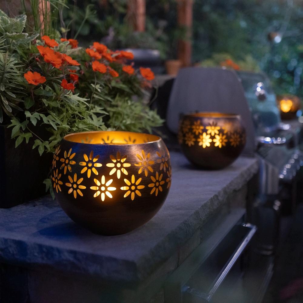 Decorative lanterns with floral patterns on a stone ledge outdoors.