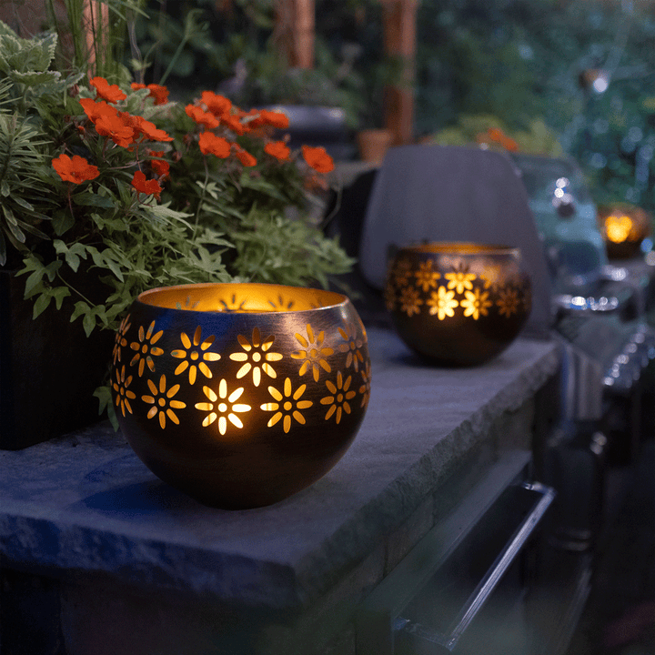 Decorative lanterns with floral patterns on a stone ledge outdoors.